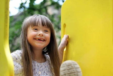 Young girl with special needs plays on a jungle gym outside